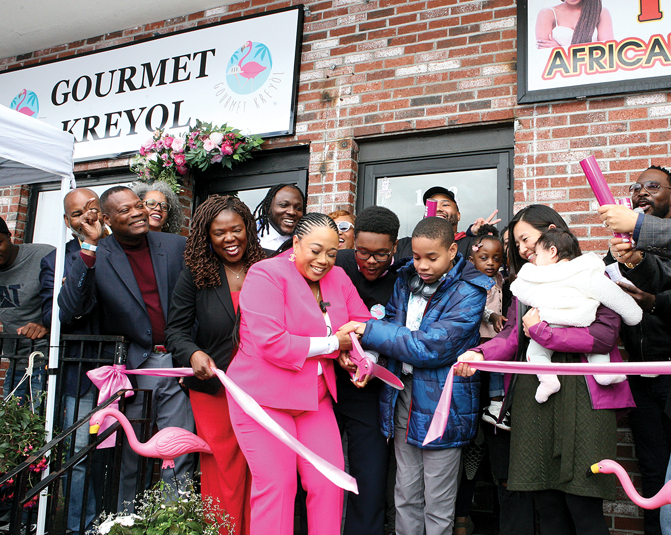 Gourmet Kreyol owner Nathalie Lecorps cuts the ribbon on the new Gourmet Kreyol location on Blue Hill Avenue Saturday afternoon, joining family, friends, Mayor Michelle Wu, and Council President Ruthzee Louijeune.