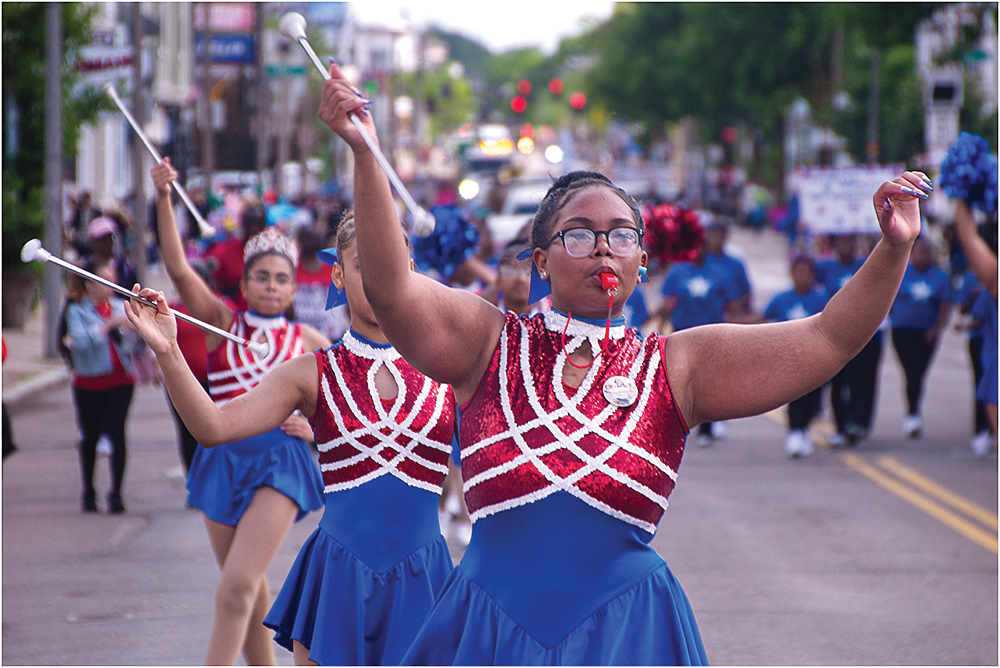 Above, Co-captain Lizbeth Presinal, of the popular dance troupe Estrellas Tropicales, is shown marching through Fields Corner. Chris Lovett photo