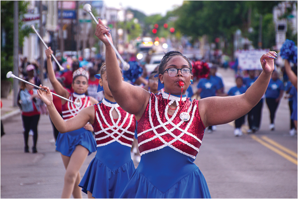 Above, Co-captain Lizbeth Presinal, of the popular dance troupe Estrellas Tropicales, is shown marching through Fields Corner. Chris Lovett photo